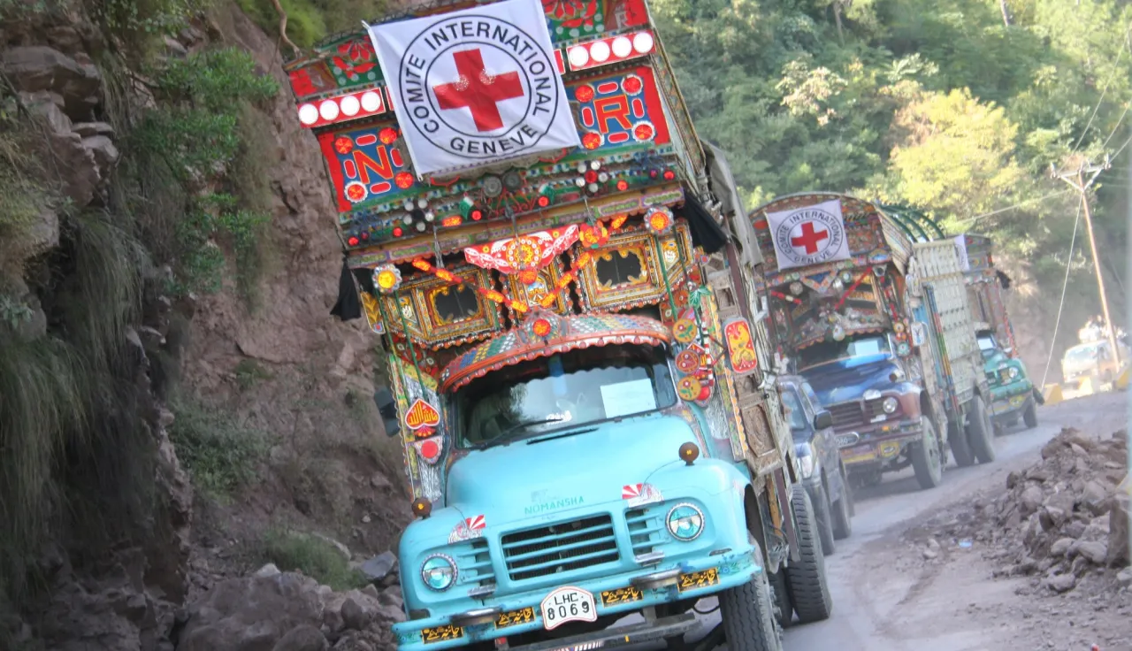 Un convoy del CICR decorado al estilo tradicional paquistaní avanza por una carretera montañosa en el valle de Jhelum, Pakistán, transportando mantas y alimentos. 